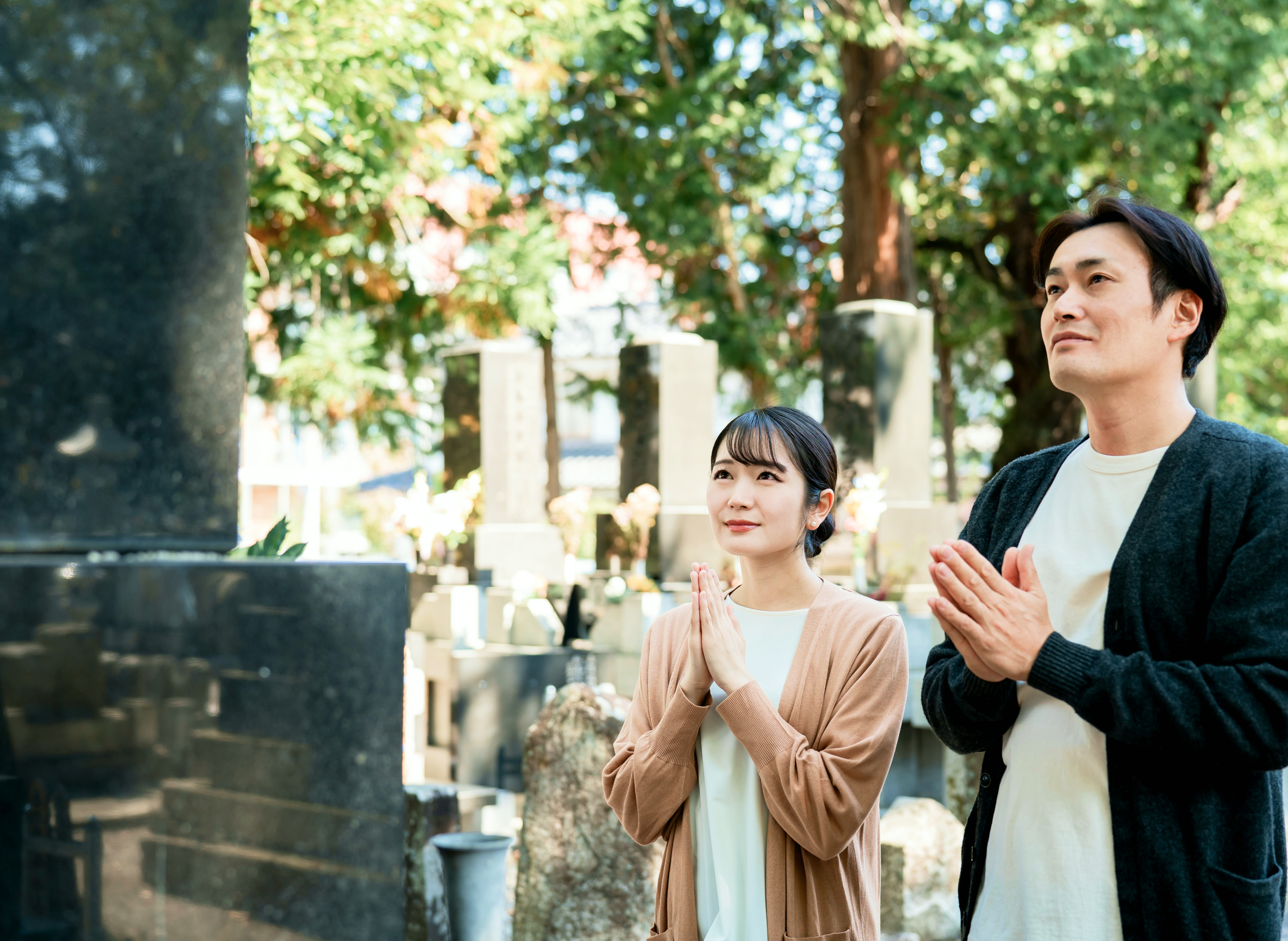 緑に囲まれた墓地で手を合わせるご夫婦